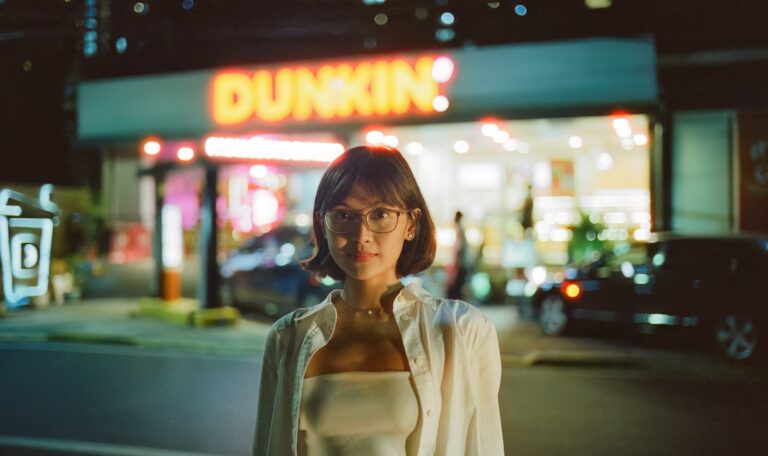 a woman standing in front of a dunkin'donuts store