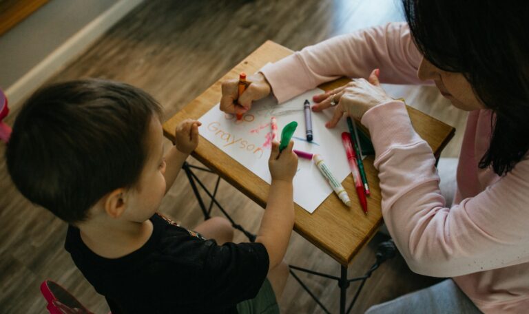 boy in white long sleeve shirt writing on white paper